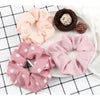 A set of three pink and mauve knitted hair scrunchie headbands displayed on a white plate.