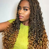 Eine Frau mit langen, lockigen Haaren in bohèmeartigen Häkel-Box-Zöpfen blickt in die Kamera.