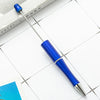 A blue beadable ballpoint pen is shown resting on a white surface next to a book.