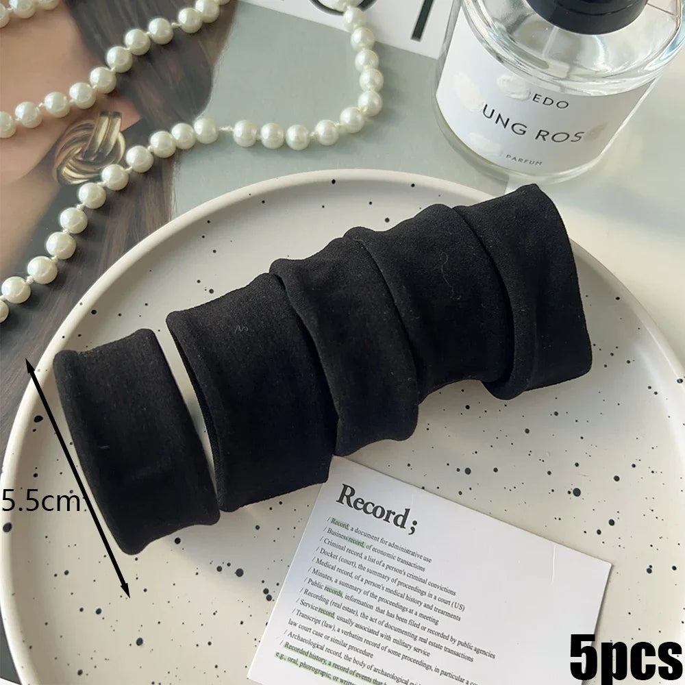 Black extra-wide elastic hair bands for ponytails displayed on a white plate.