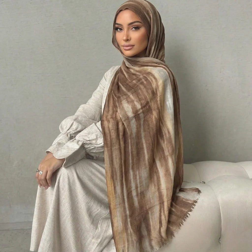 Una mujer vistiendo un pañuelo de hijab a rayas marrón y beige y un vestido de color claro.