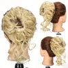 A woman's head showing a blonde hair bun hairstyle with long, wavy extensions.