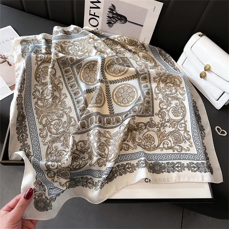 A beige and gold patterned silk scarf draped on a white card against a dark background.