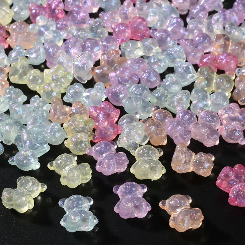 A close-up view of numerous luminous glow-in-the-dark acrylic beads in shades of pink, purple, and pale yellow scattered on a