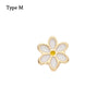 Un pequeño adorno de pulsera de metal con forma de flor, centro blanco y acento amarillo.