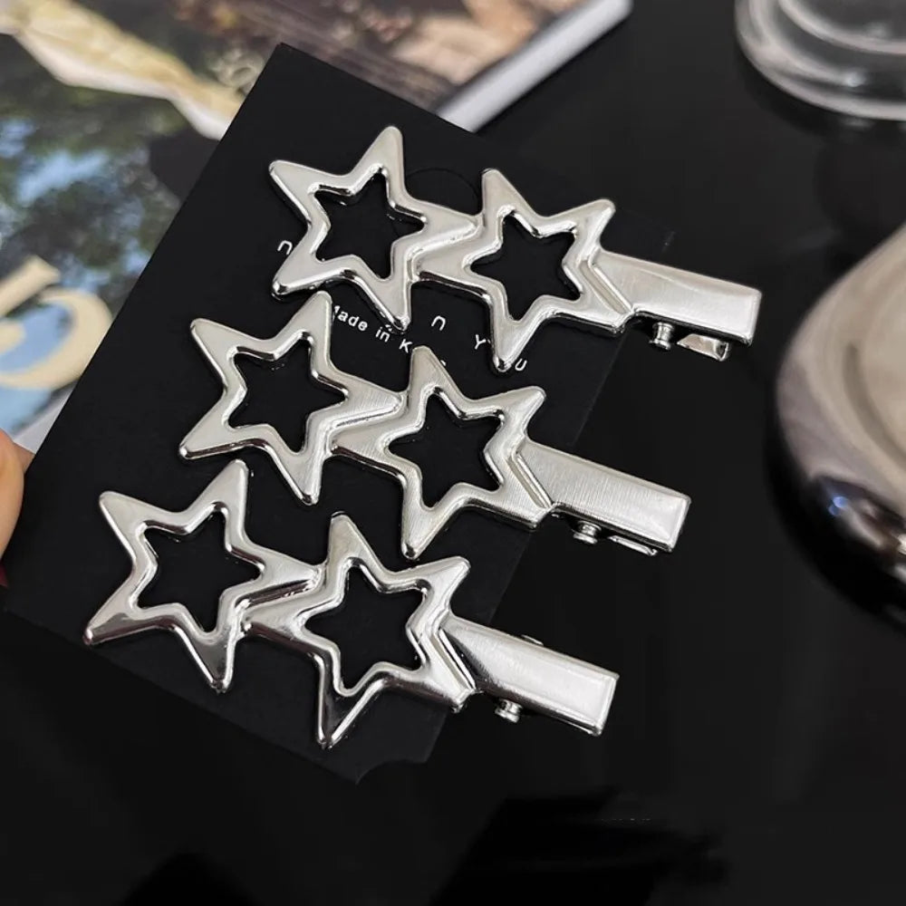 A set of five silver star-shaped metal hair clips displayed on a black surface.