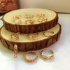 A set of gold-toned adjustable open toe rings displayed on a wooden slice.