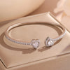 A set of geometric rhinestone heart stacking bracelets displayed on a light beige box.