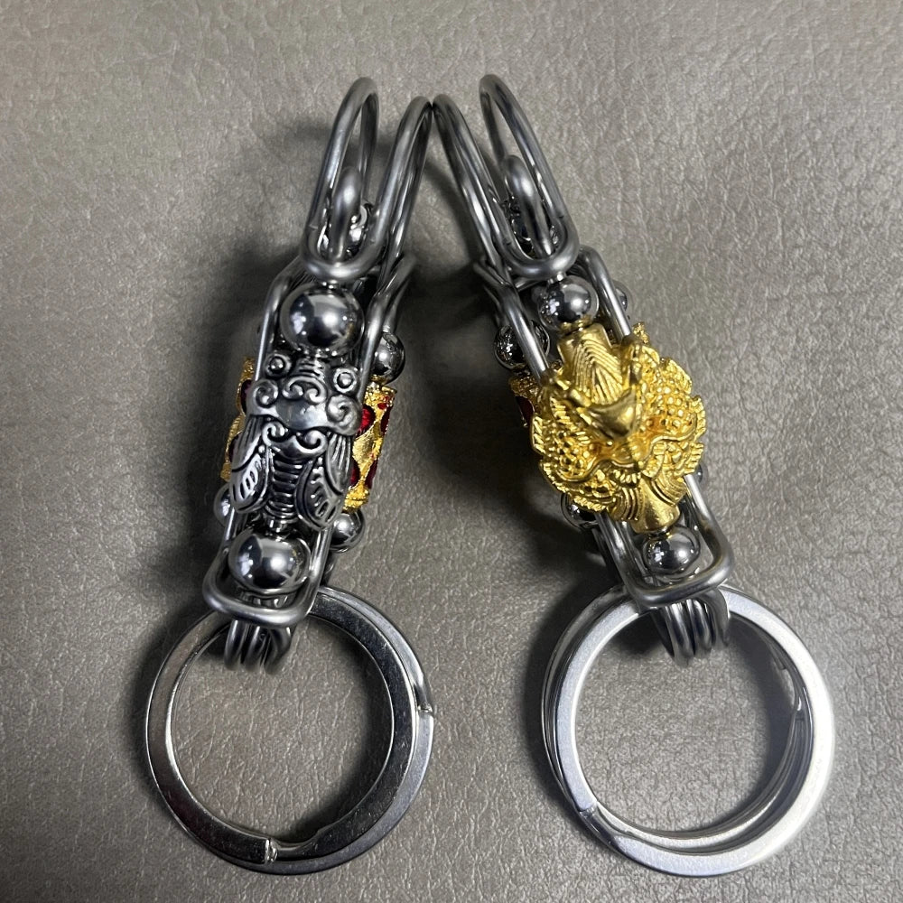 Une paire de porte-clés mécaniques en acier inoxydable avec des designs complexes et des accents dorés.