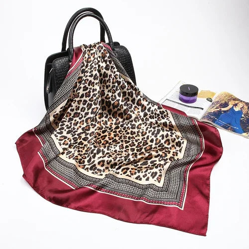 Maroones Seidenschal mit Leopardenmuster, drapiert über ein schwarzes Accessoire.