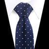 A dark blue patterned silk necktie with white polka dots worn under a white dress shirt.