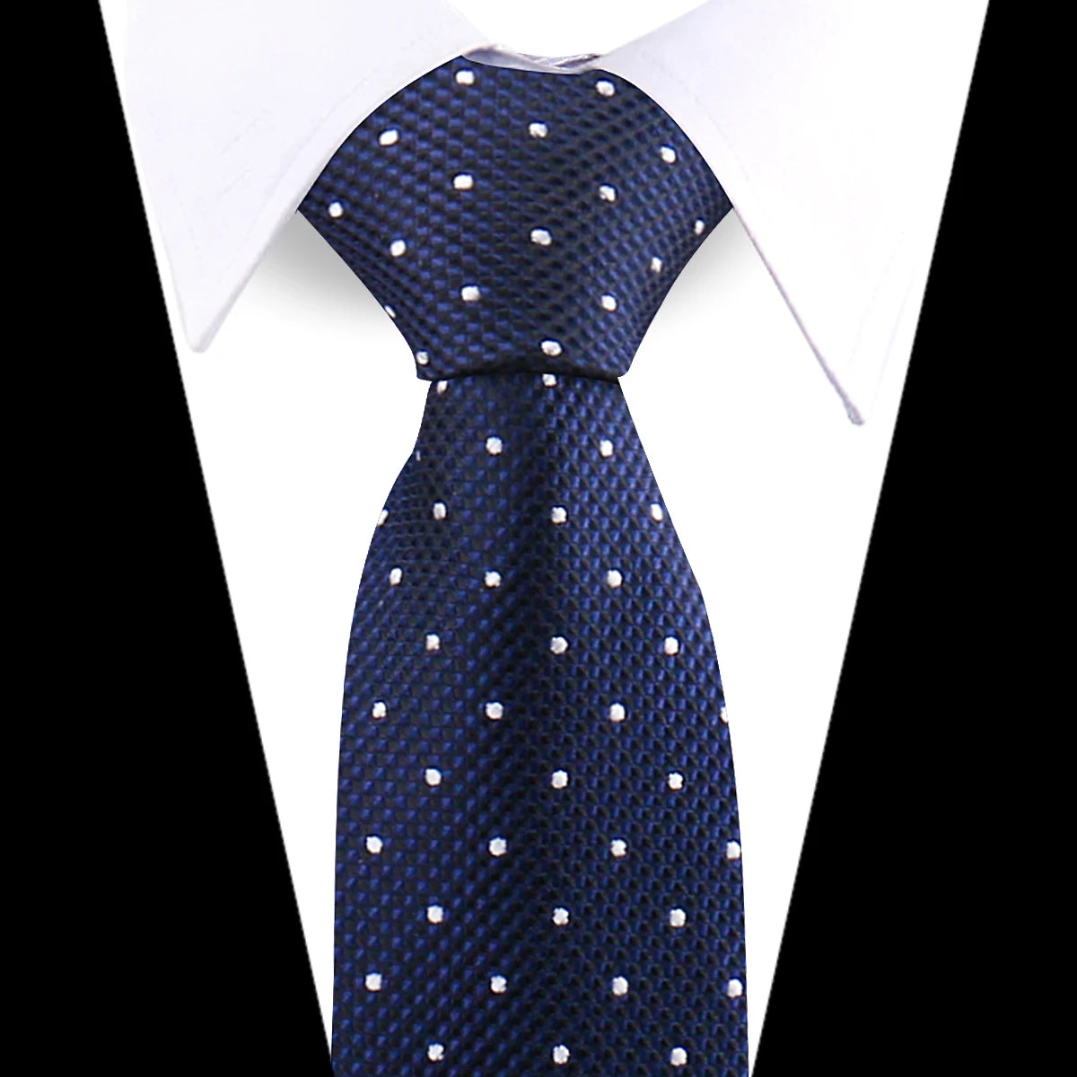 A dark blue patterned silk necktie with white polka dots worn under a white dress shirt.