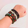 A hand is wearing several stacked fashion elastic wood bead bracelets with various colors and beads.