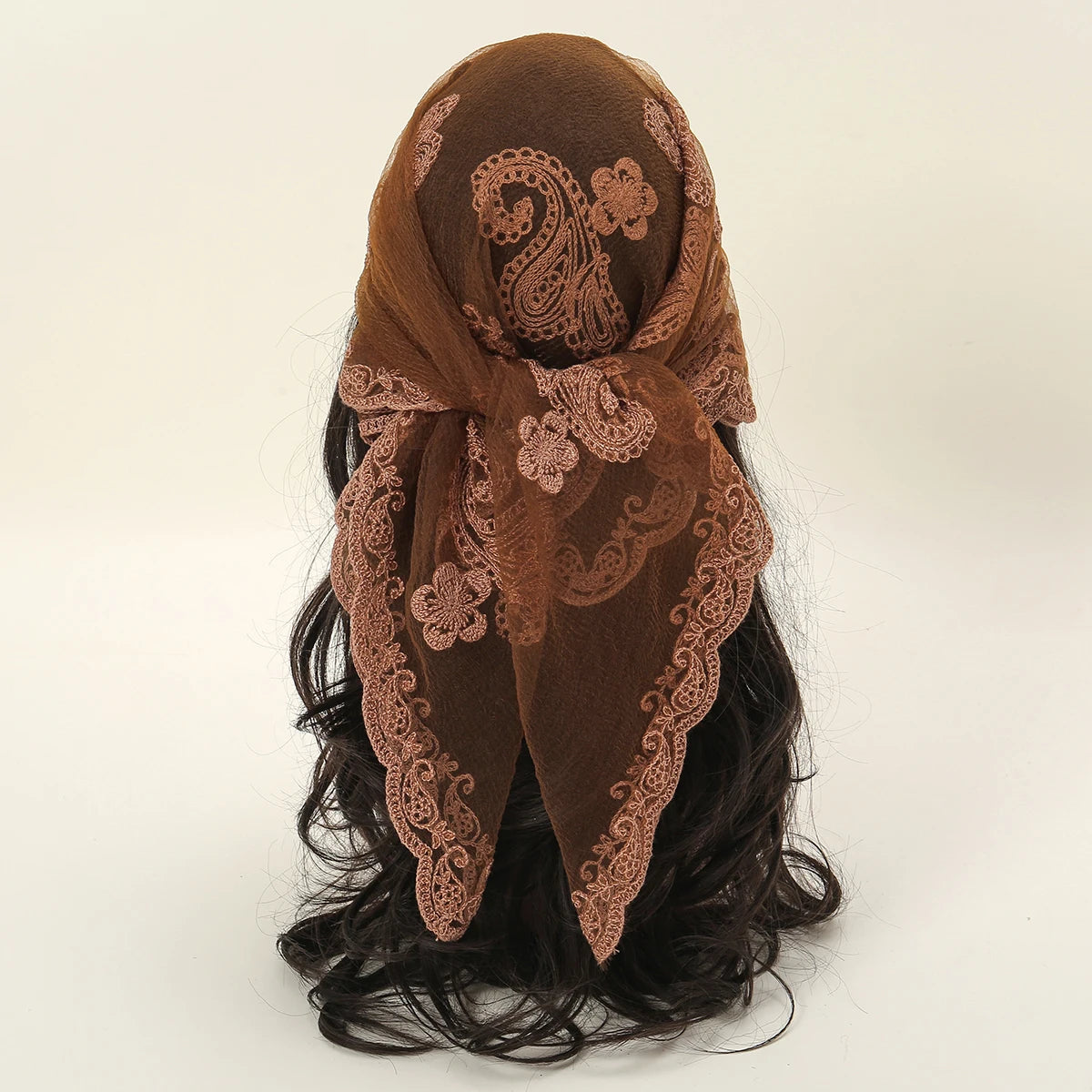 A brown floral embroidered lace bandana headscarf tied around a person's hair.