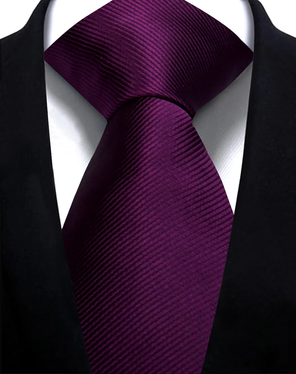 Nahaufnahme einer schmalen, klassischen, dunkelvioletten Jacquard-Krawatte für Herren, getragen gegen eine schwarze Sakkojack