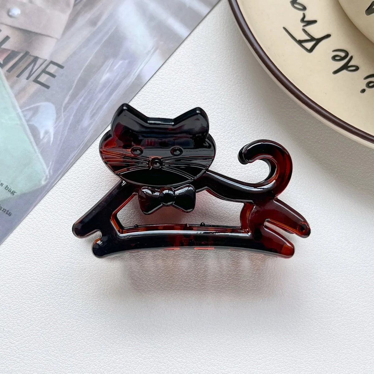A glossy dark amber cat hair clip featuring a cartoon style design.