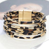 Une pile de bracelets de perles en cuir léopard bohèmes avec accents dorés, exposés sur une surface blanche.