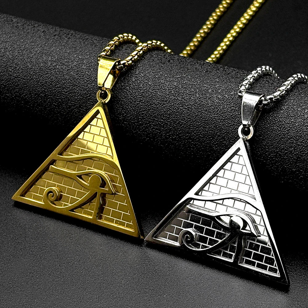 Colgante de collar con el ojo triangular de Horus en oro y plata, exhibido sobre una superficie negra.