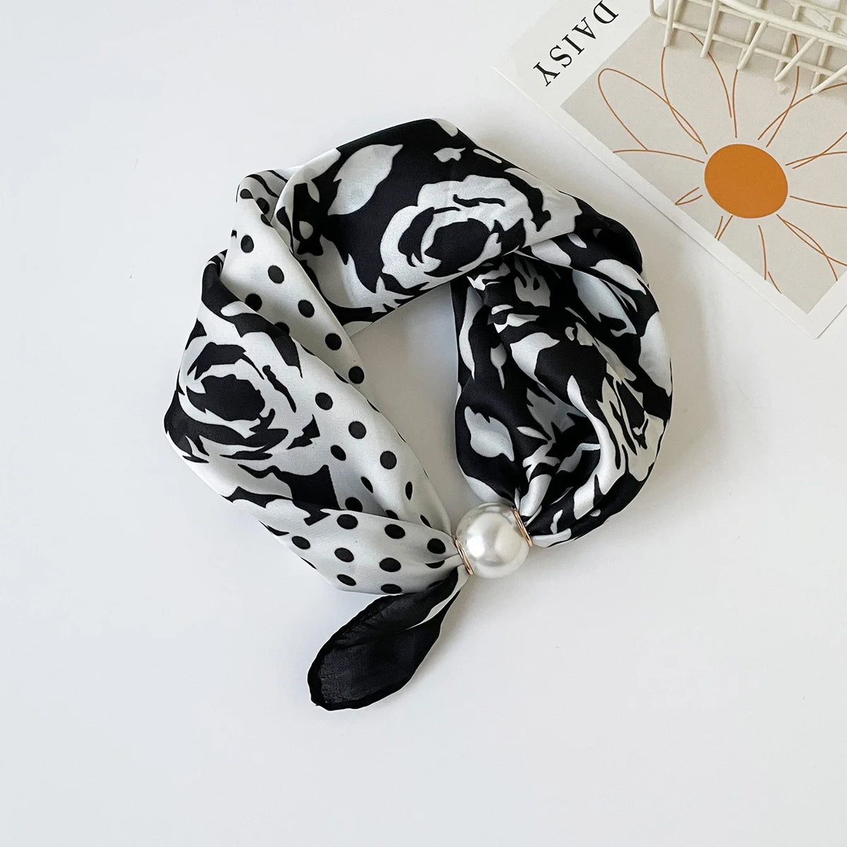 Black and white floral silk scarf tied around a pearl bead.