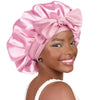 A woman wearing a pink satin sleeping bonnet tied in a large bow.