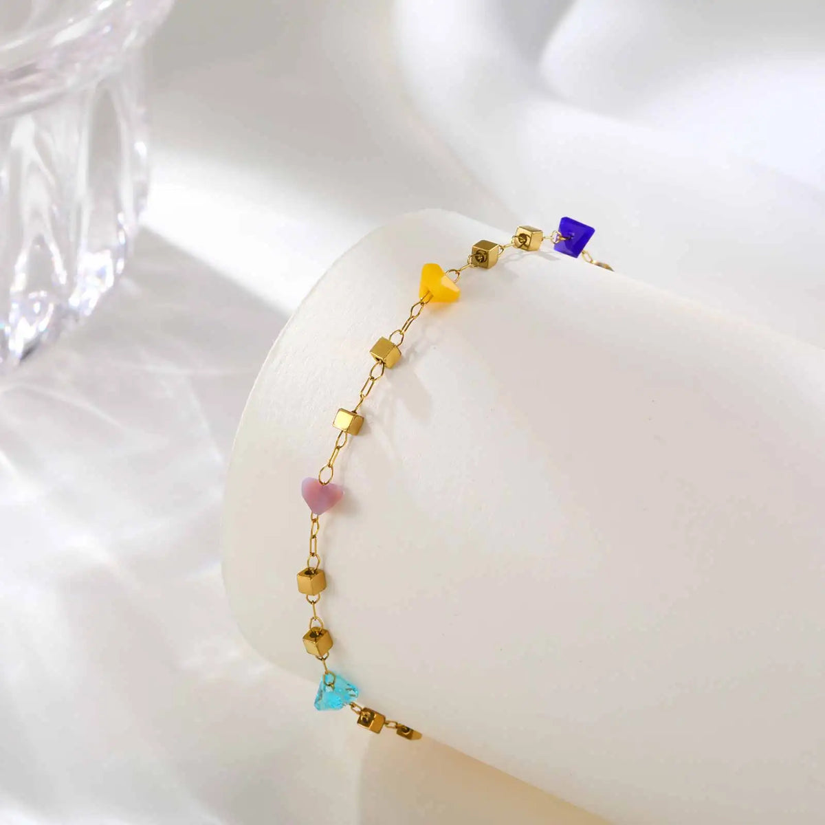 A gold-toned necklace featuring irregular colored gemstone beads, including purple, yellow, pink, and blue.