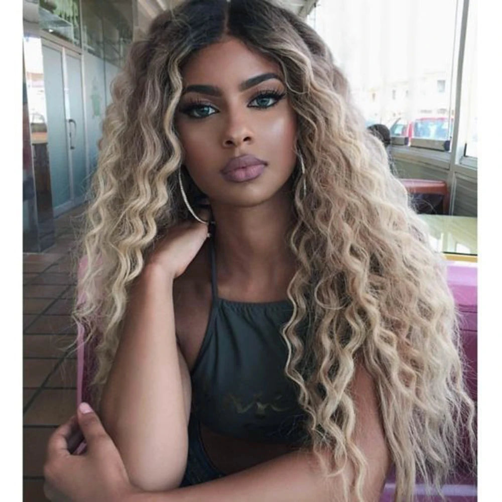 Eine Frau mit langen, gewellten blonden Haaren trägt ein dunkles Oberteil in natürlichem Licht.