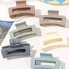 A set of seven square hair claw clips in various muted tones, including beige, gray, and blue-green.