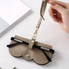 A tan PU leather pouch and glasses case with a leather strap is shown against a white background.