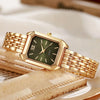 A gold minimalist quartz watch with a square face and bracelet resting on a light-colored surface.