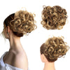 A woman's hair styled in a voluminous, curly chignon or messy bun using a synthetic hairpiece.