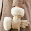 Tan plush wrist gloves with white faux fur cuffs worn on a person's hand.