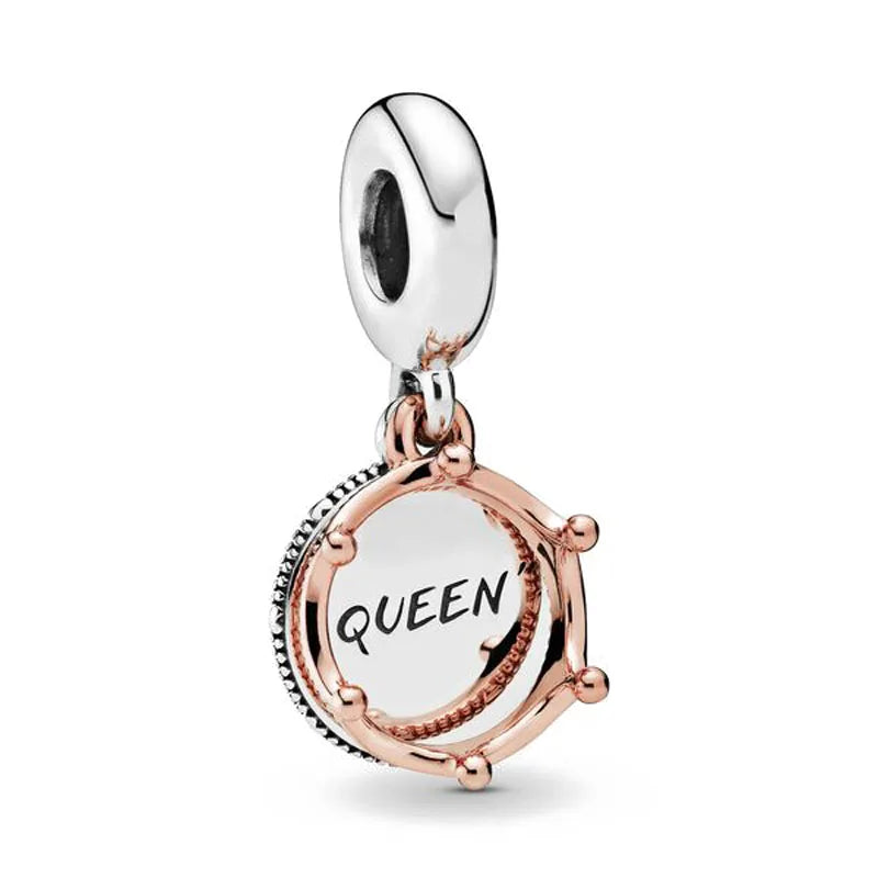 A rose gold cherry blossom charm pendant with a silver bail and a round disc engraved with the word QUEEN.