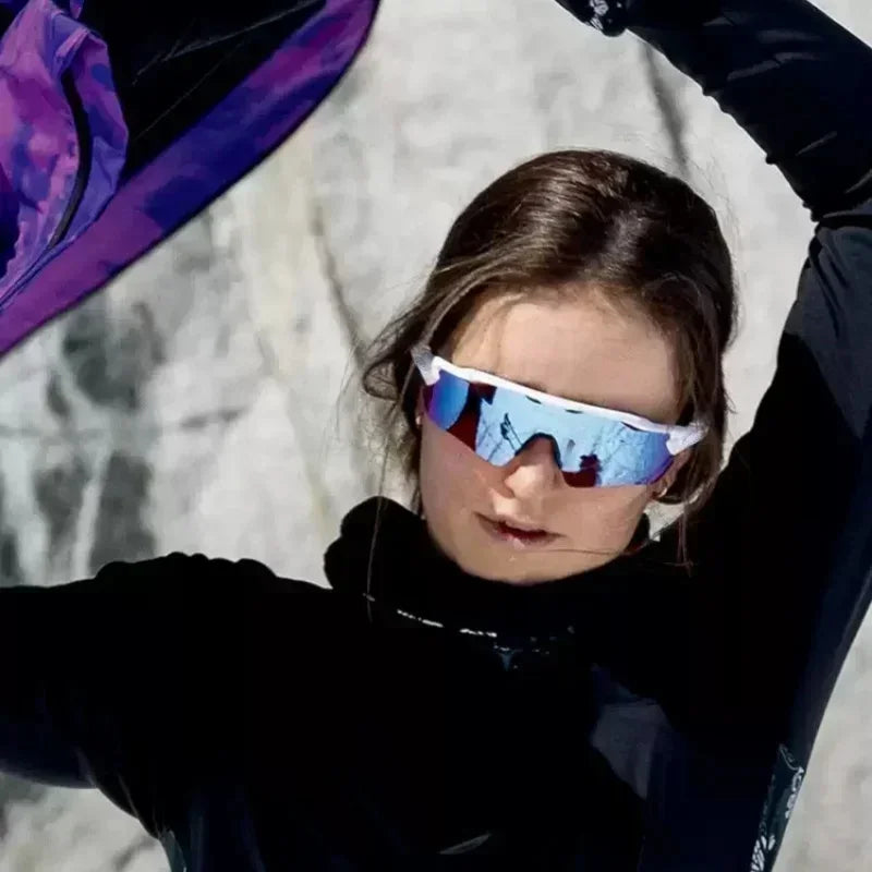 A young person wearing blue mirrored cycling sunglasses with a white frame against a light background.