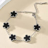 Silver-toned bracelet featuring four black flower charms on a silver chain.