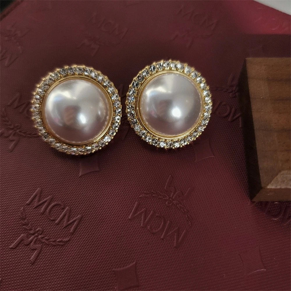 Un set de collier et boucles d'oreilles en strass élégants sur un fond de velours rouge foncé.