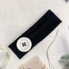 Black stretch hairband with a white circular detail and natural twine nearby