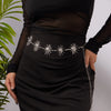 A woman wearing a black dress with a silver heart waist chain body jewelry on her waist.