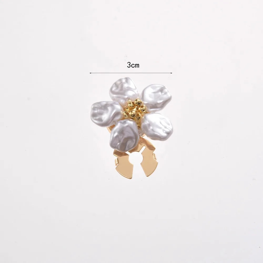 A small floral button cufflink featuring white pearl-like flowers and gold accents.