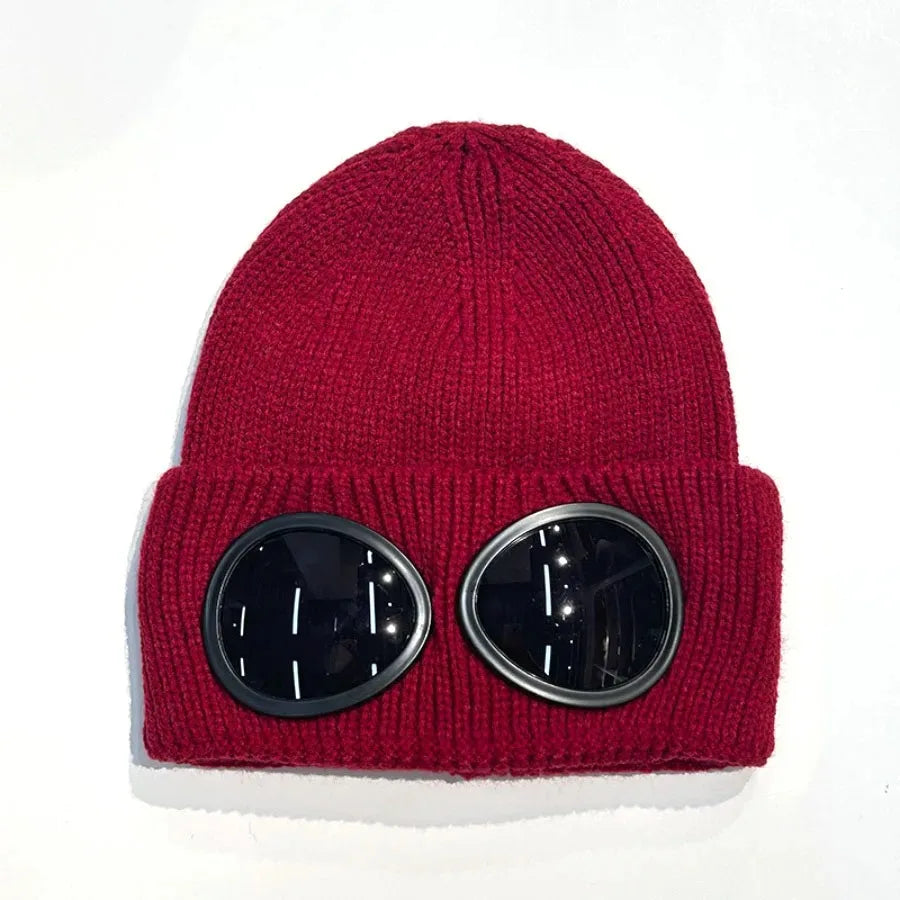 A maroon knit windproof hat with round, silver-rimmed goggles.