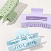 A set of seven square hair claw clips in various pastel shades, including green, purple, and light blue.