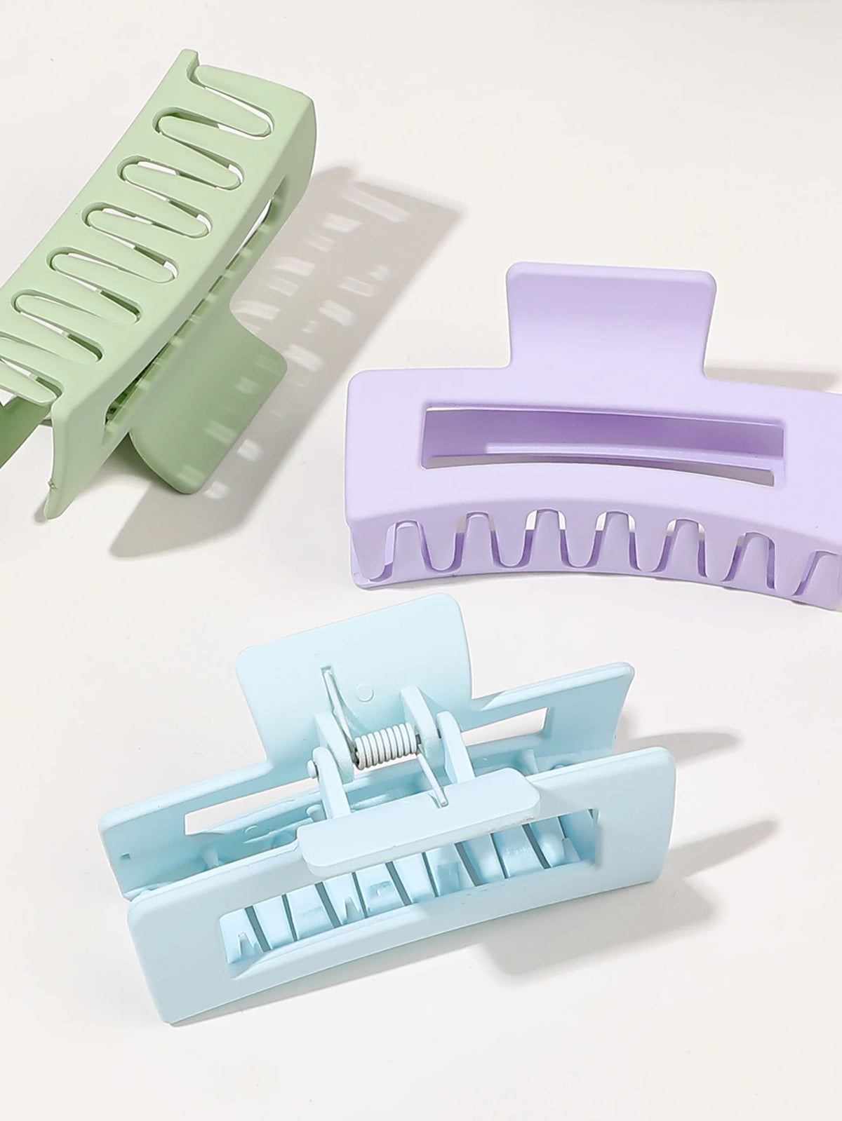 A set of seven square hair claw clips in various pastel shades, including green, purple, and light blue.