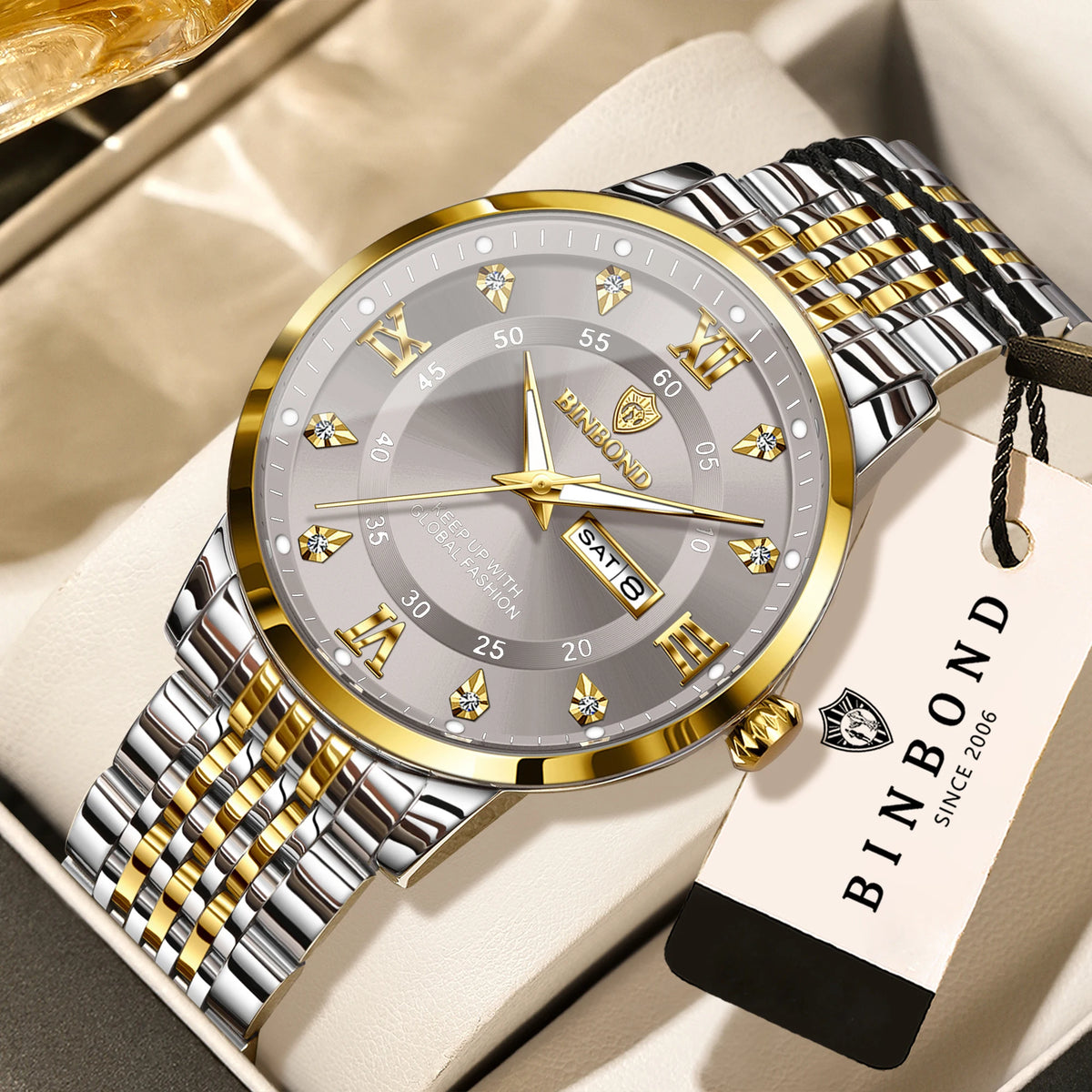 A silver and gold Bambond wristwatch with a metal bracelet resting on a light beige surface.