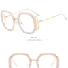 A pair of light pink khaki-colored eyeglasses frames with gold accents.