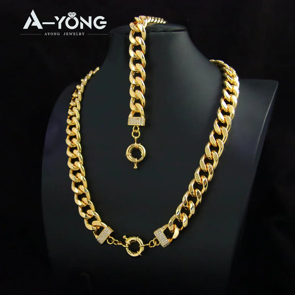 A gold plated Cuban chain necklace with a pendant and bar accents displayed on a black display stand.
