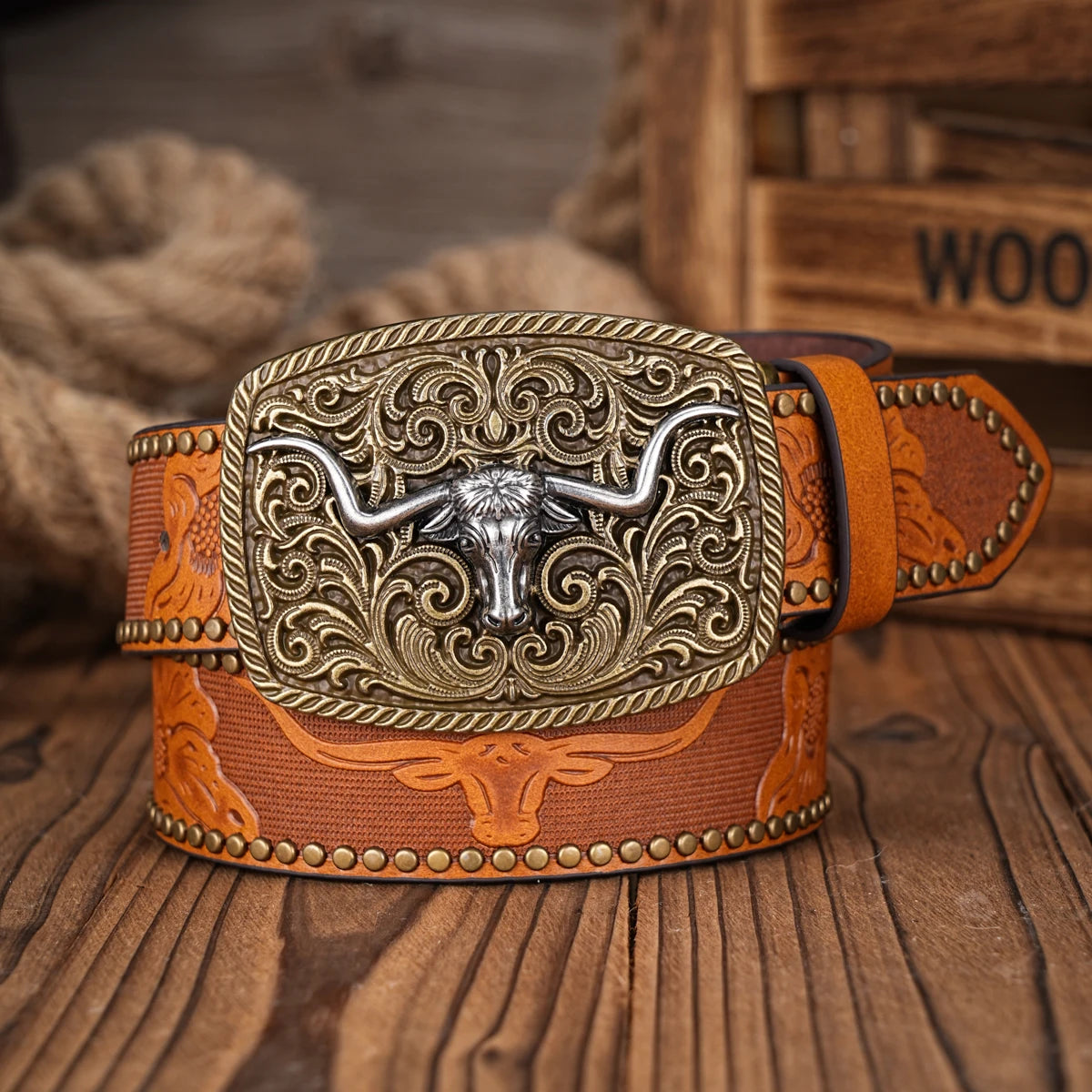 A brown PU leather belt with an engraved silver bull head buckle and floral pattern resting on a wooden surface.