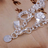 A silver geometric charm bracelet featuring various charms and links displayed on a wooden surface.