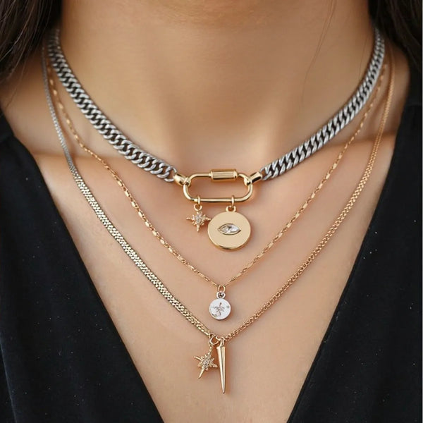 A multilayered gold necklace featuring a chain with a silver-black link and various pendants including a star and an eye moti