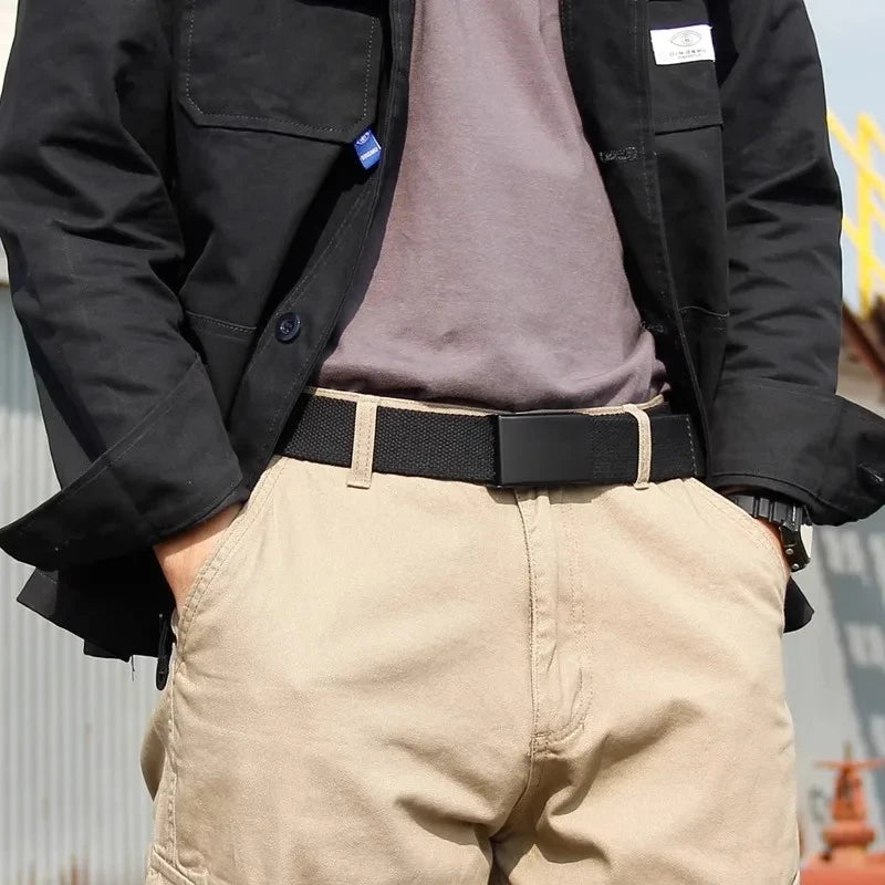 A person wearing a black jacket, gray shirt, and tan pants with a black tactical waist belt.