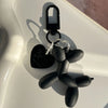 A black jelly cartoon dog keychain with a silver chain and hook resting on a white surface.