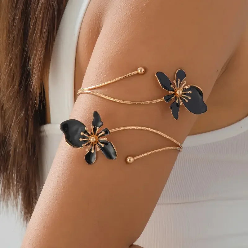 Gold-toned floral open cuff armlet jewelry worn on a person's wrist.